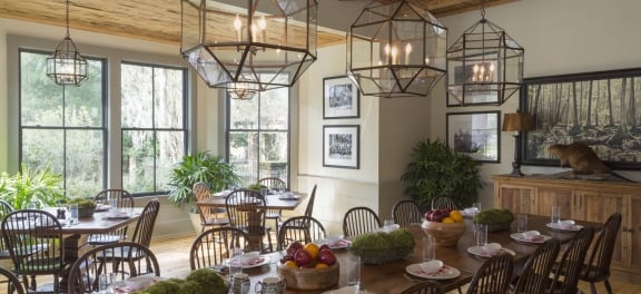 The Broadfield Lodge Dining Room. A bright room with wooden beam ceilings, long banquet table and four seaters set for breakfast.