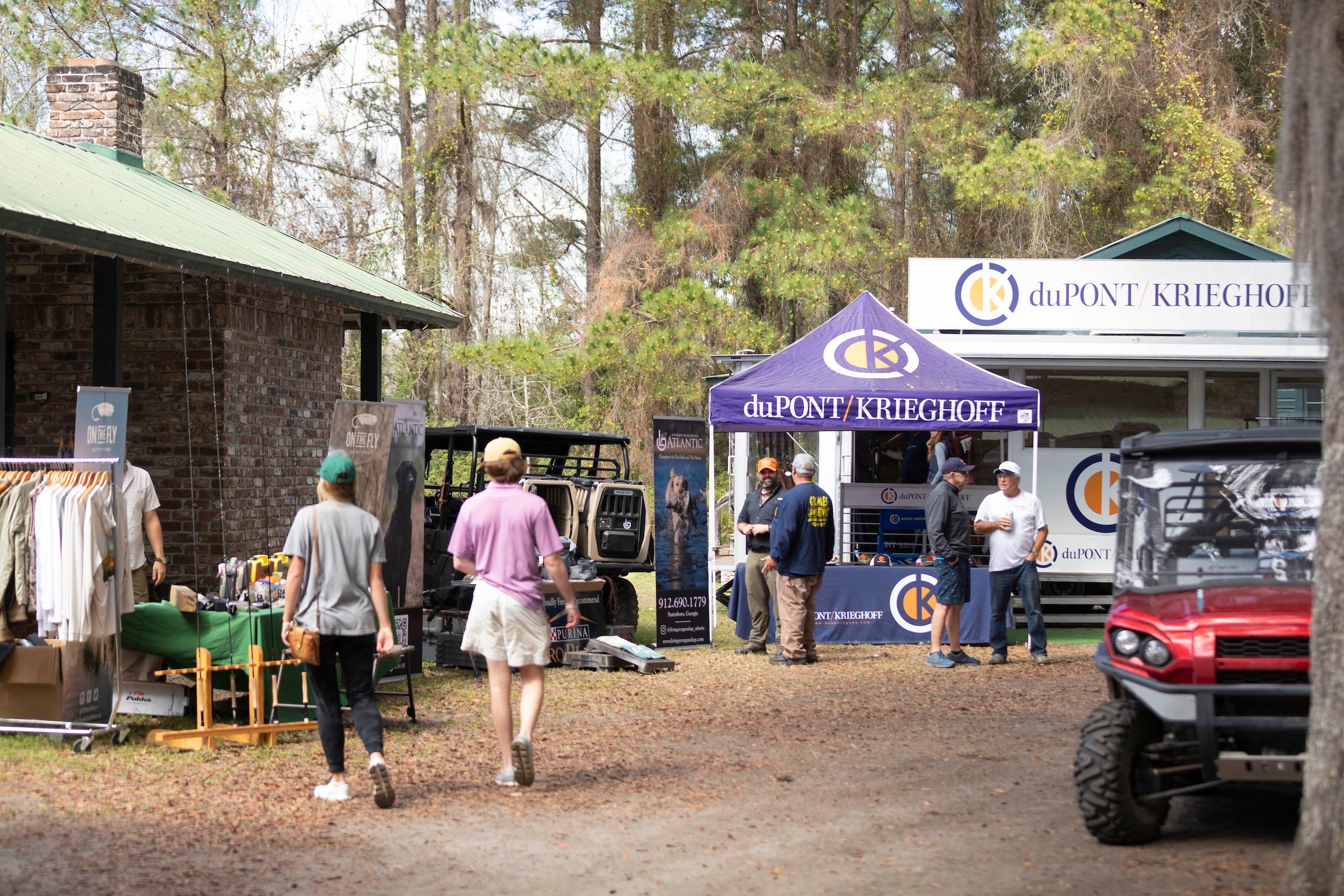 A few people walk along the outdoor vendor area of the Seminole Cup on a sunny day.