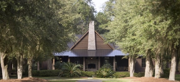 The Broadfield Lodge, a large modern cabin with mature trees on either side of the drive way.