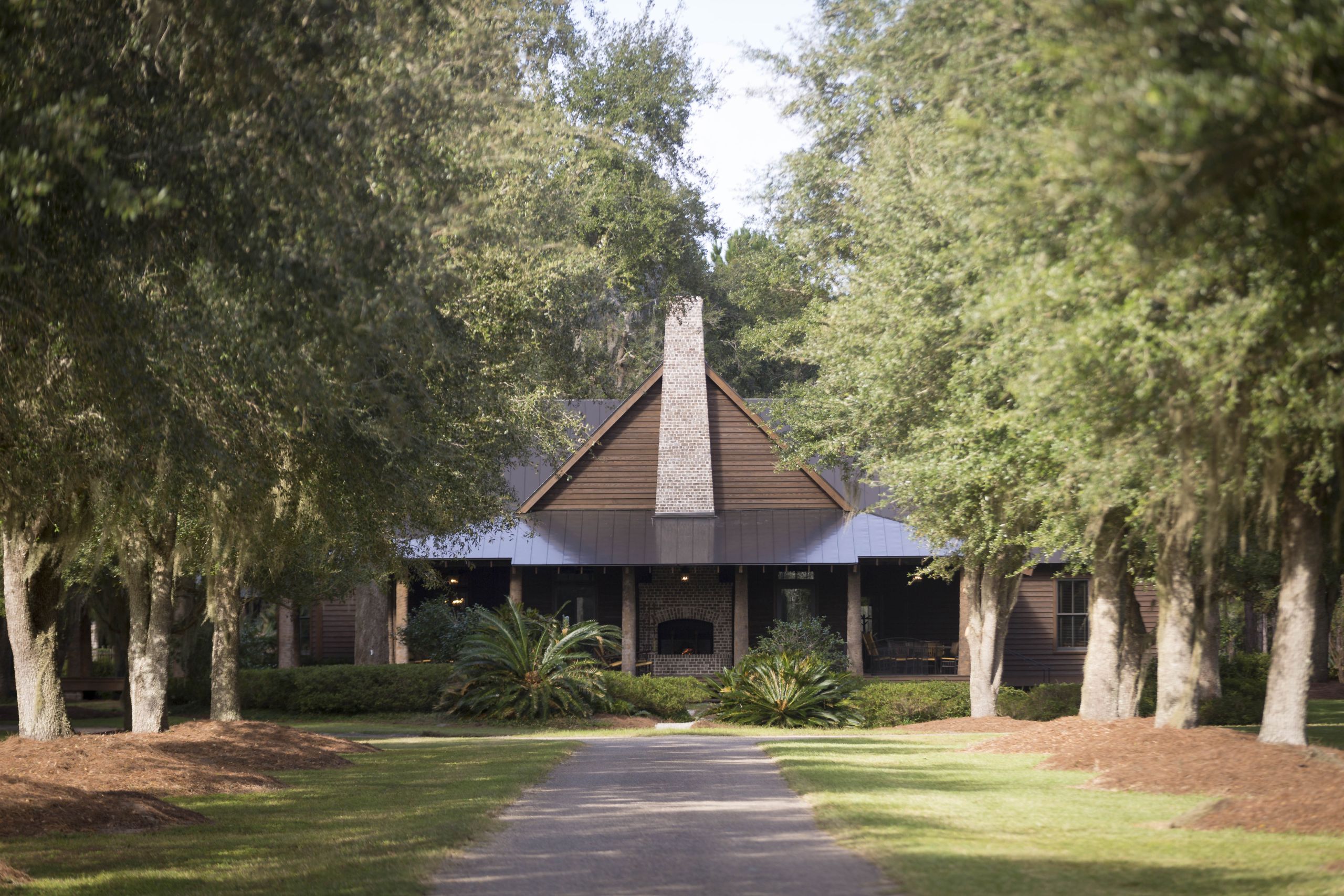 The Broadfield Lodge, a large modern cabin with mature trees on either side of the drive way.