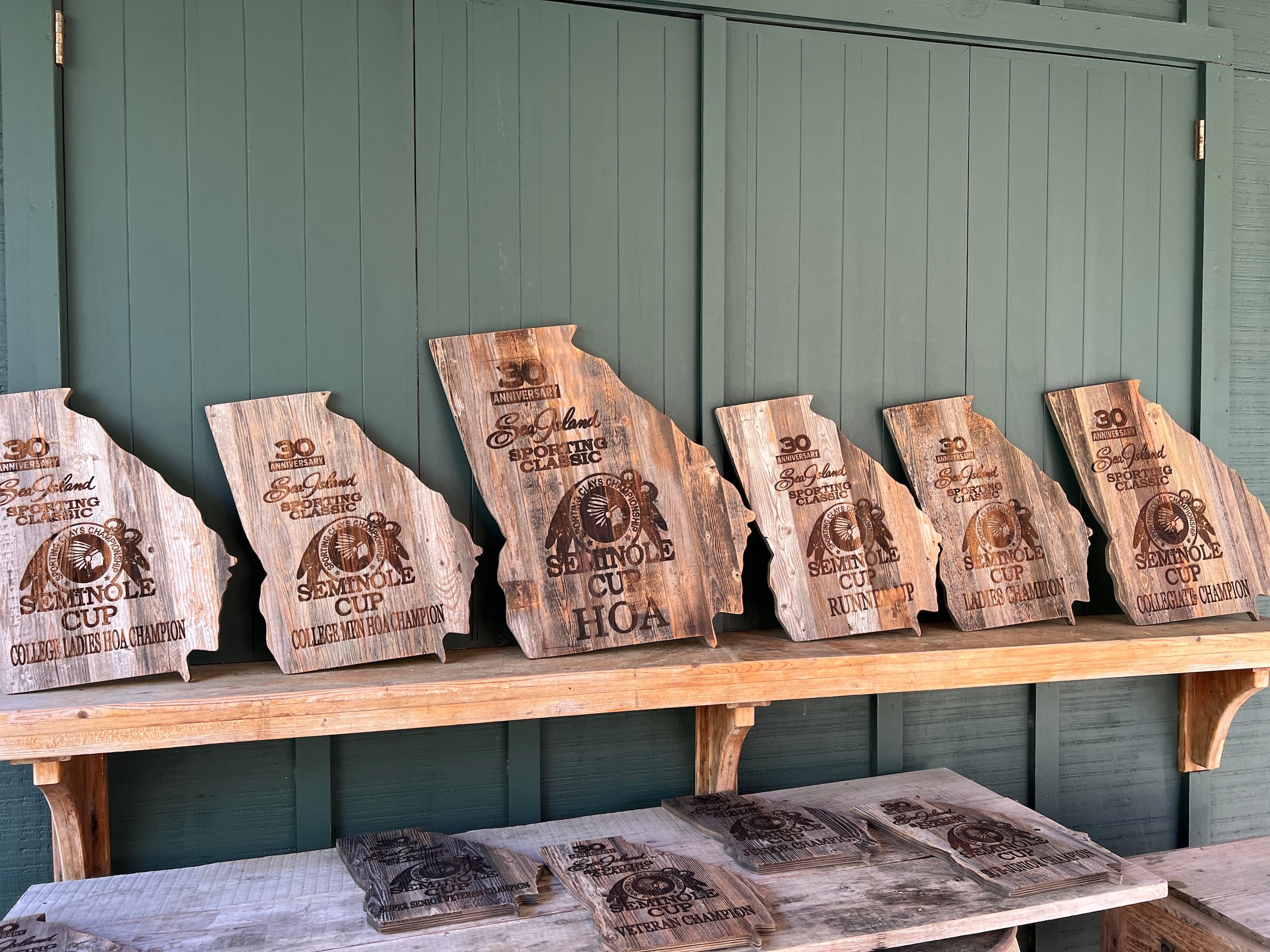 10 wooden Seminole Cup awards in the shape of Georgia lined up on a shelf.