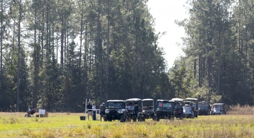 Golf carts lined up in a field behind a sporting clay competition.